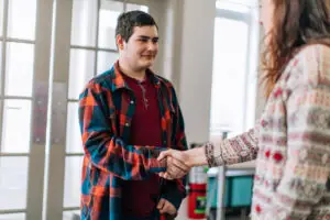 A young woman and a teenage boy shaking hands. Social services, social worker, psychologist, psychiatrist, foster home, student and teacher
